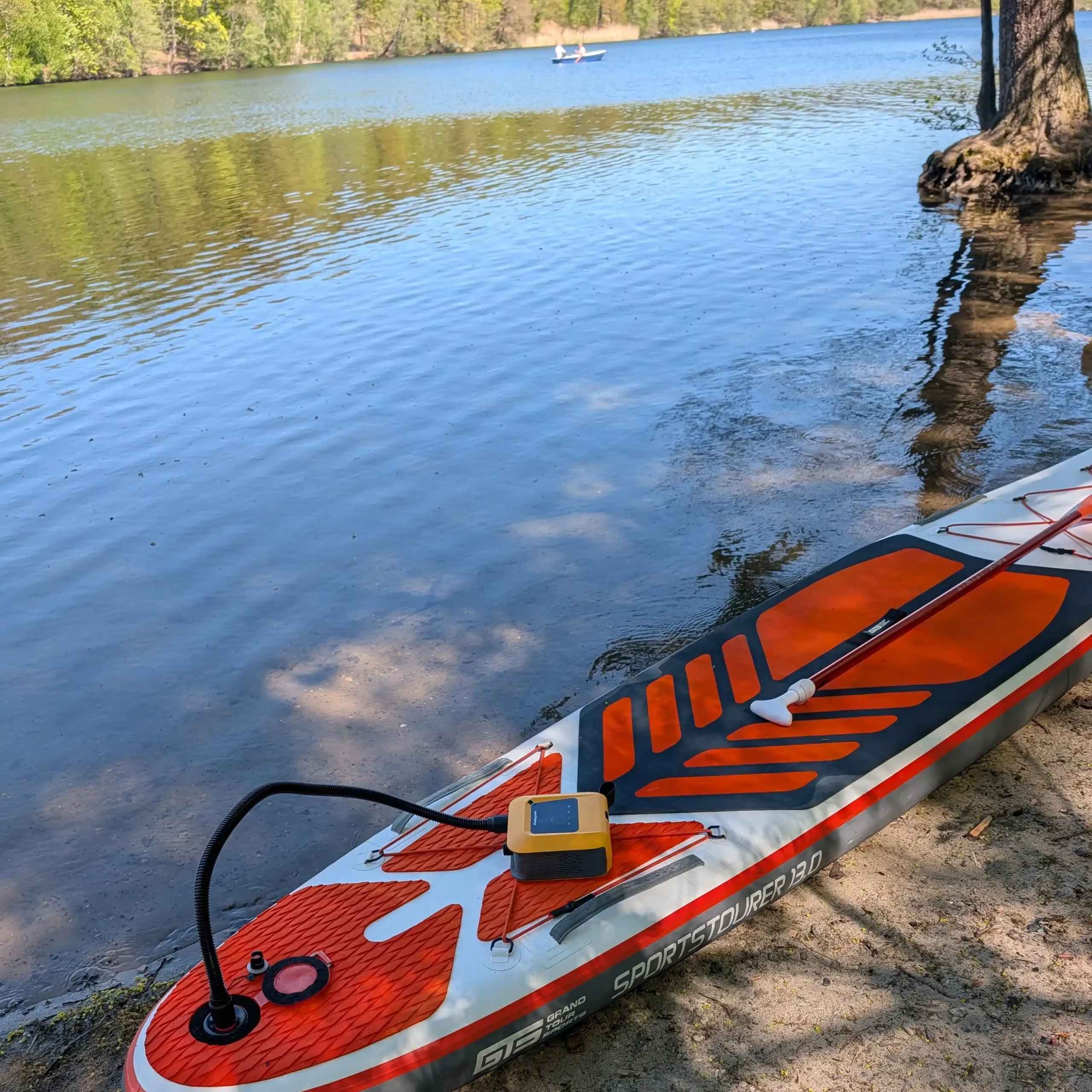 Peakspeak 20PSI electric SUP pump next to inflatable paddle board gear